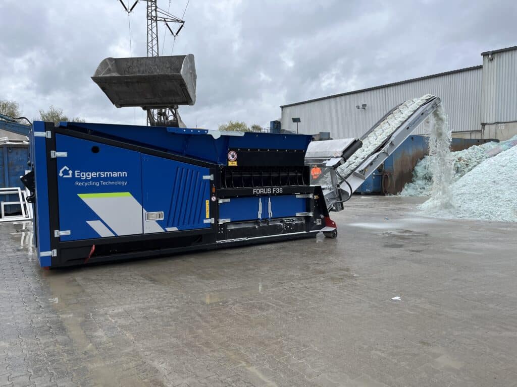 Broyeur Eggersmann FORUS F38 traitant des déchets avec un convoyeur dans un centre de recyclage industriel.