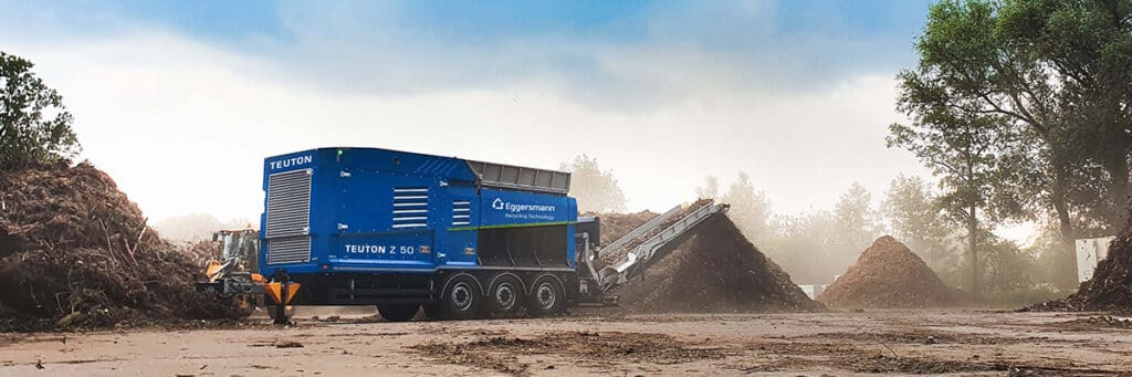 Broyeur mobile Teuton Z 50 Eggersmann recyclant des déchets de bois en extérieur avec son convoyeur.